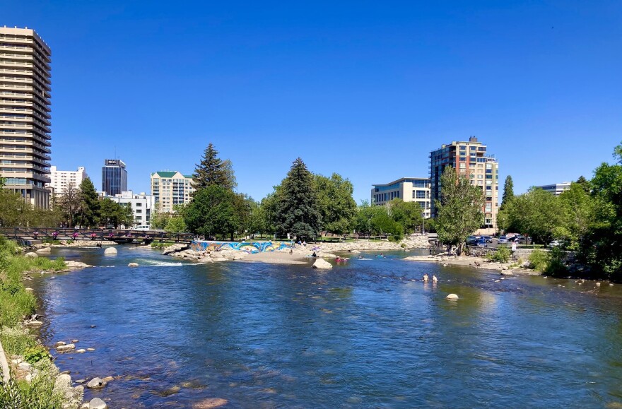 A wide shot of the Truckee River flowing near Downtown Reno in Nevada. People can be seen cooling off in the water.