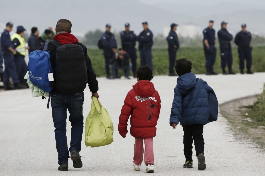 A migrant and children carry their belongings at the Idomeni camp on Tuesday. In an operation that began shortly after sunrise, hundreds of Greek police began evacuating the sprawling camp.