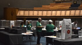 Volunteers talk before helping observe or process ballots for the Primary Elections.