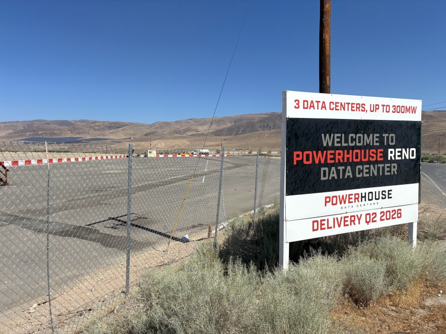 This is an image of a fenced-off development site, backdropped by brown mountains. On the right of the image is a sign that says "Welcome to Powerhouse Reno Data Center."