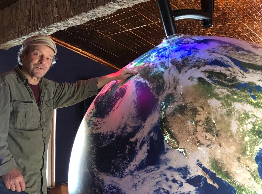 Artist Eric James Morris points out Fairbanks on a giant spherical model of Earth at the soon-to-be opened Aurora Discovery Institute at Pike’s Waterfront Lodge in Fairbanks. (Robyne/KUAC)