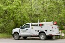 An Ameren Missouri utility truck is parked on a residential city street in Columbia Missouri. Behind the truck the frame is filled with lush green trees. 