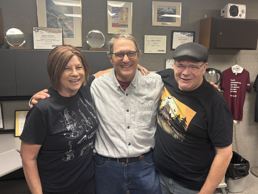 Linda Smith, B.G. Bradley, and Marty Achatz stand arm in arm and smile just outside of Public Radio 90’s Studio A.