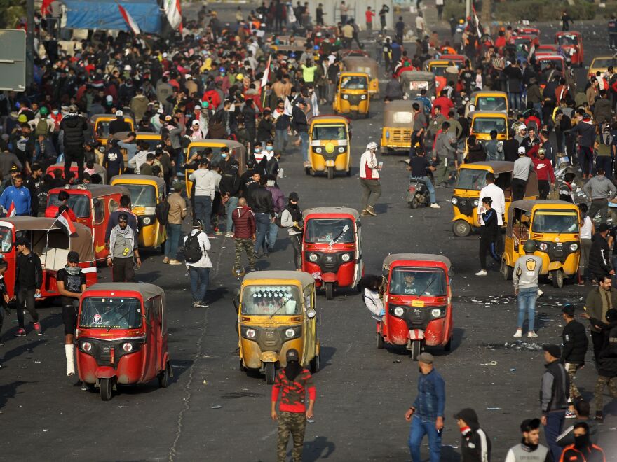 Iraqi protesters and tuk-tuk drivers gather amid clashes with riot police following a demonstration in Baghdad on Monday.