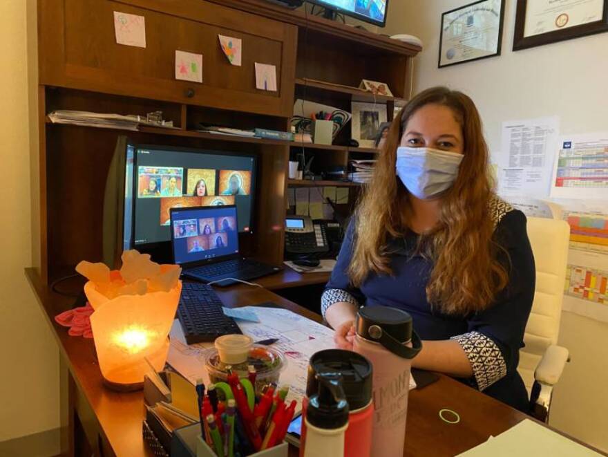 A masked woman sitting at an office desk