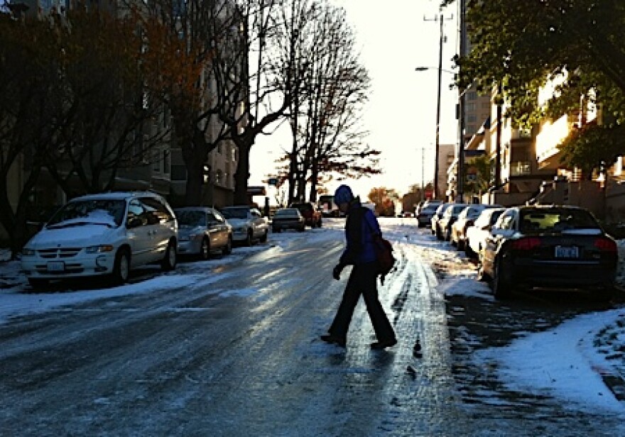 A woman walks gingerly across icy Boylston Avenue on Seattle's First Hill Tuesday morning. The street had a thick layer of compact snow and ice, like many in the region.