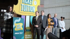Governor Gretchen Whitmer standing behind a "Ticket to Tuition" logo on a podium alongside several other people on stage