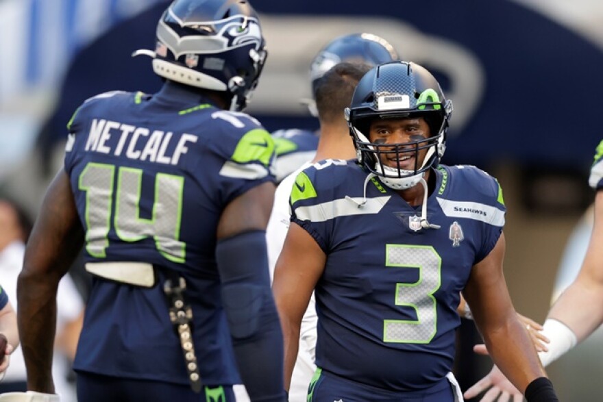 Seahawks quarterback Russell Wilson (3) greets wide receiver DK Metcalf (14) during warmups before the team's NFL football preseason game against the Los Angeles Chargers, Saturday, Aug. 28, 2021, in Seattle.