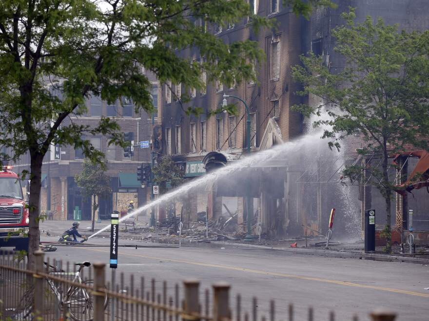 A firefighter directs water on a building that houses El Nuevo Rodeo, a club where George Floyd and Derek Chauvin both worked at one time, former owner Maya Santamaria told KSTP.