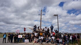 A crowd of people gather together to pose for a photo, holding signs like "keep job corps."
