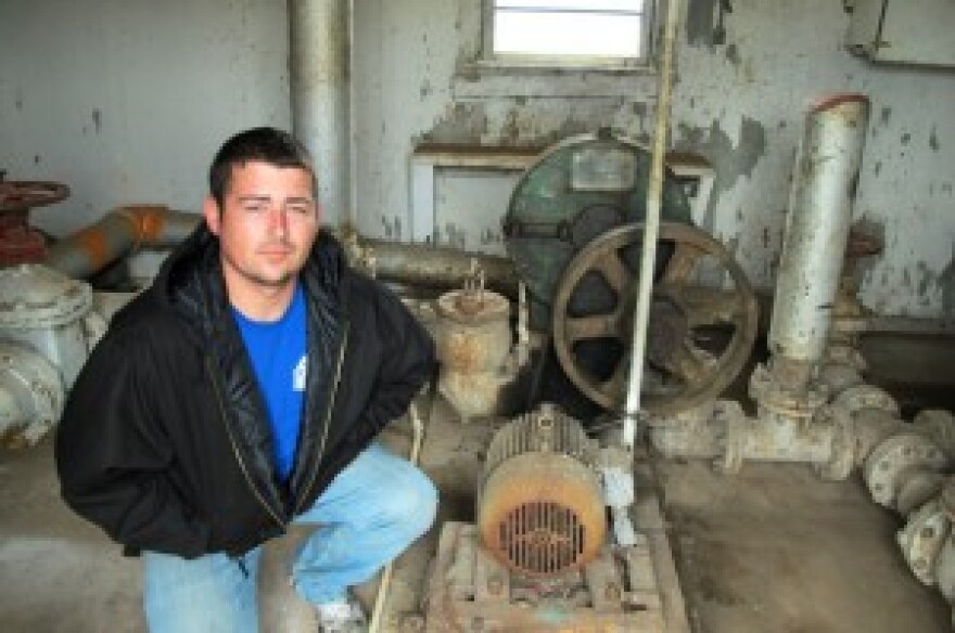 Justin Johnston crouching by sludge pump