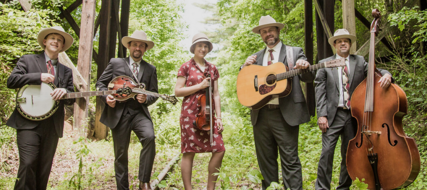 Male and female members of the band standing in the forest with their instruments