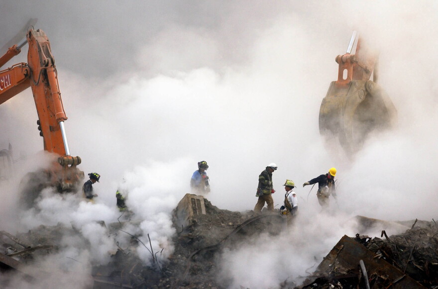 FILE - In this Oct. 11, 2001 file photo, firefighters make their way over the ruins of the World Trade Center through clouds of dust and smoke at ground zero in New York. With the Oct. 3, 2013 deadline looming, more than 32,000 people have applied to the federal compensation fund for people with illnesses that might be related to toxic fallout from the attacks, program officials said. (AP Photo/Stan Honda, Pool, File)