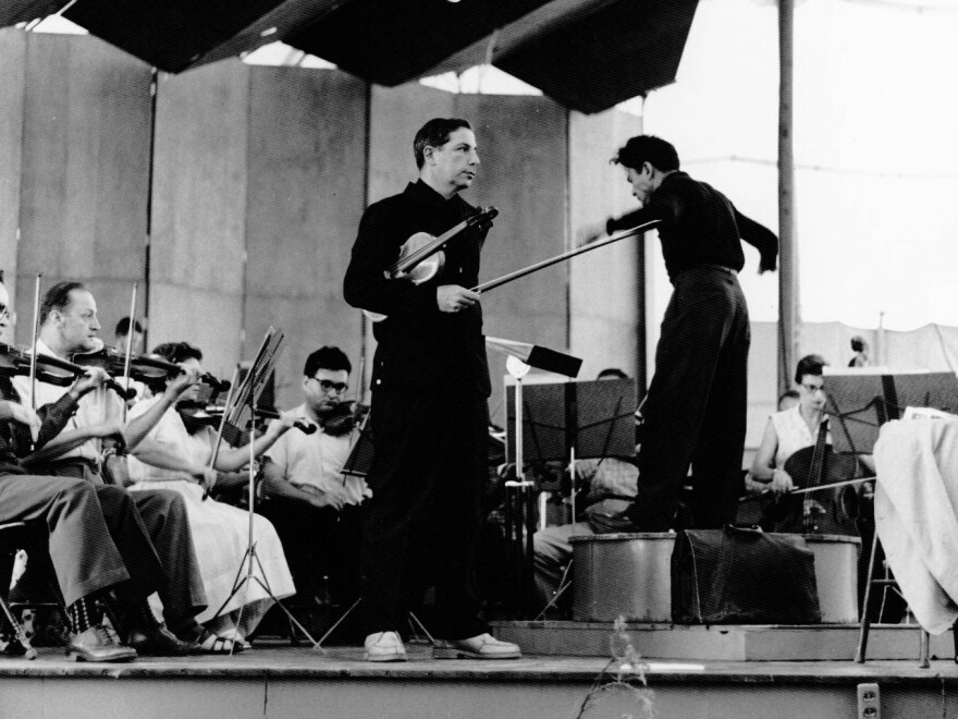Totenberg holds his Stradivarius before a rehearsal in Aspen, Colo., in the late 1950s. Izler Solomon (right) conducts the orchestra.