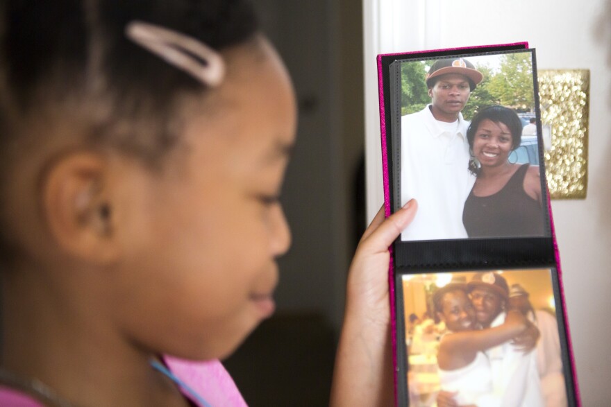 Karisma Clark, 9, holds up a photo album that includes photos of her mom and dad. Her dad passed away when she was very young but Karisma has written about the strength and confidence that he gave her.