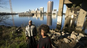 From Left: Sharon Endrick, President of the Campostella Civic League, and Kim Sudderth, a community activist, at the edge of the Elizabeth River under the Berkley Bridge with the skyline of the City of Norfolk Friday afternoon, December 15, 2023. Residents of the Southside neighborhoods were furious to learn their communities, with predominantly Black populations, would not get the same floodwall protections as downtown Norfolk.
