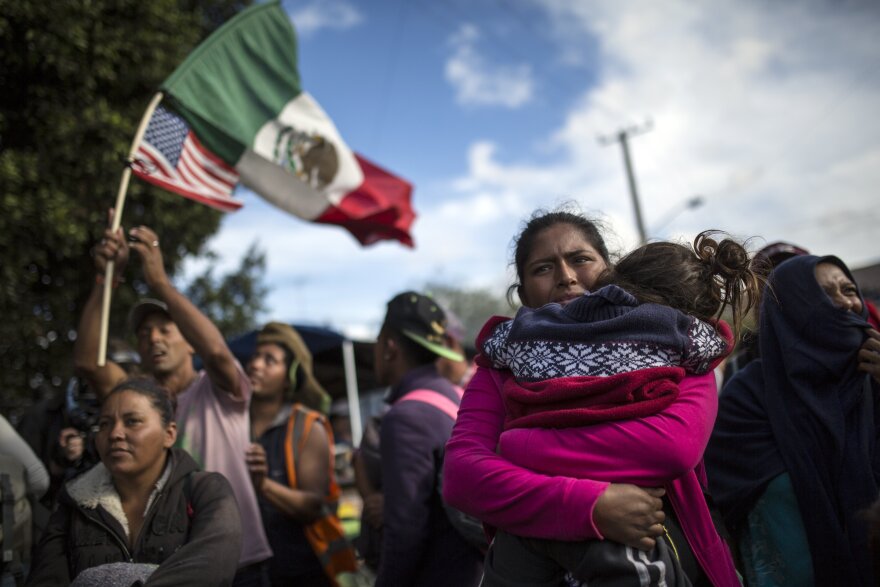 Honduran migrant Leticia Nunes holds her daughter Mailyn as she and others stand in front of a line of Mexican police in riot gear, when they tried to cross the Chaparral border crossing in Tijuana, Mexico, Thursday, Nov. 22, 2018.