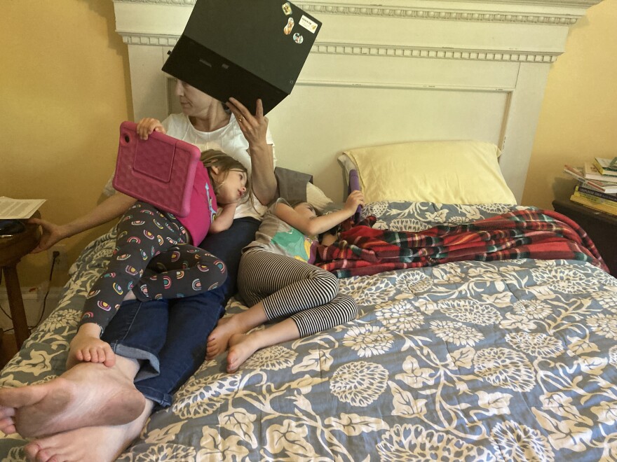 Beagan Wilcox Volz works on her computer as daughters Karen (left) and Anna watch videos while quarantining at home in Helena, Montana, on Sept. 24, 2021.