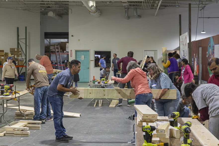 Volenteers carrying a piece of wood to make a bed frame.