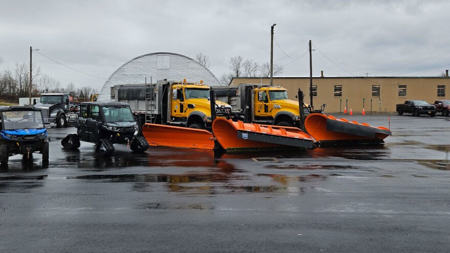 Two gray utility task vehicles, one blue and one gray, sit at Erie County Department of Public Works in Lancaster. Next to them is a pair of snowplows ready for use this winter.