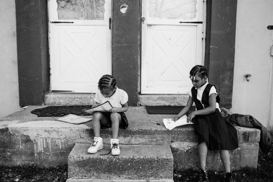 Amor Merlin and Lakeisha Merlin do homework outside their home in Barry Farm in 2016.