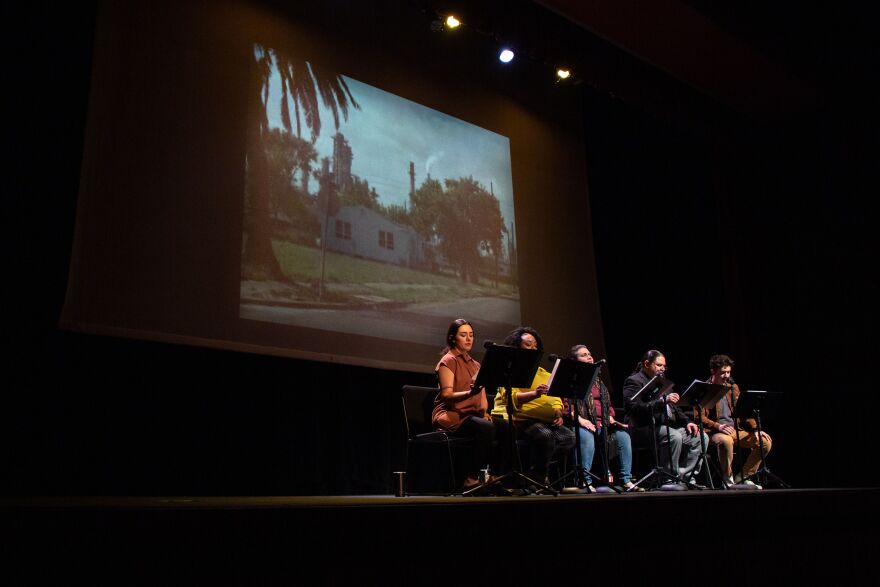 Five people sit on stage in front of a projected image of a house. 