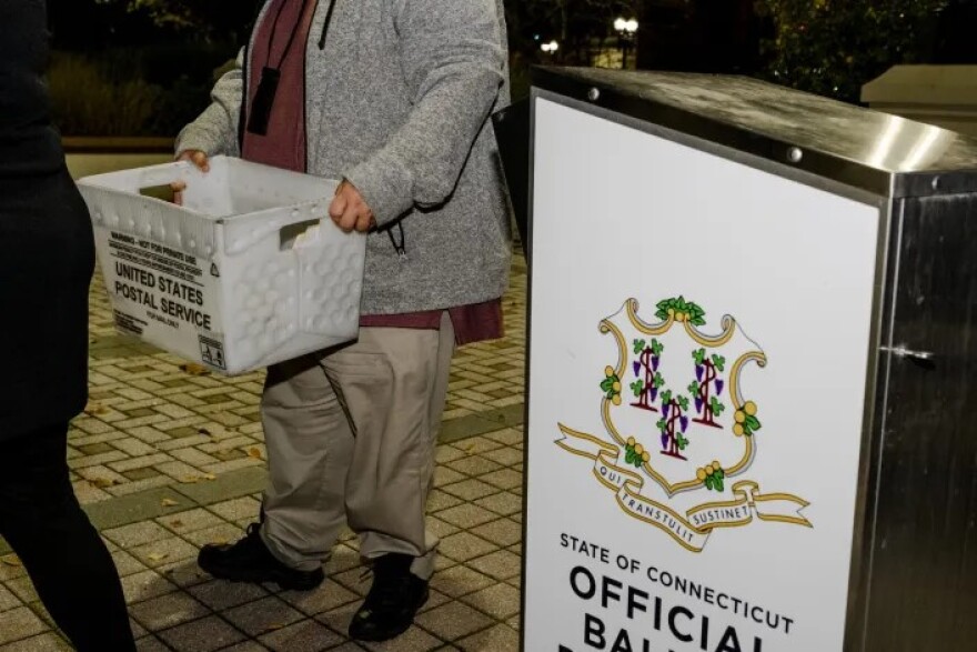 A city employee carries absentee ballots from the ballot box at Margaret E. Morton Government Center in Bridgeport on Tuesday, Nov. 7, 2023.