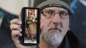 Matthew Butler, who spent 27 years in the Army, holds a 2014 photograph of himself during his last deployment in Kabul, Afghanistan. Butler is now one of the military veterans in several U.S. states who are helping convince conservative lawmakers to take cautious steps toward allowing the therapeutic use of hallucinogenic mushrooms and other psychedelic drugs. 