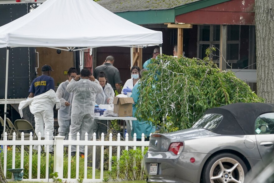 Authorities work outside as they search the home of suspect Rex Heuermann, Wednesday, July 19, 2023, in New York. Police carted more boxes of potential evidence Tuesday out of the Long Island home of Heuermann.