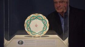 Peoria Riverfront Museum guest curator Bill Heidrich gazes at an 18th century soft-paste Sèvres porcelain plate unveiled Thursday. The plate was originally gifted in 1758 by King Louis VI of France to Maria Theresa, the Holy Roman Empress.