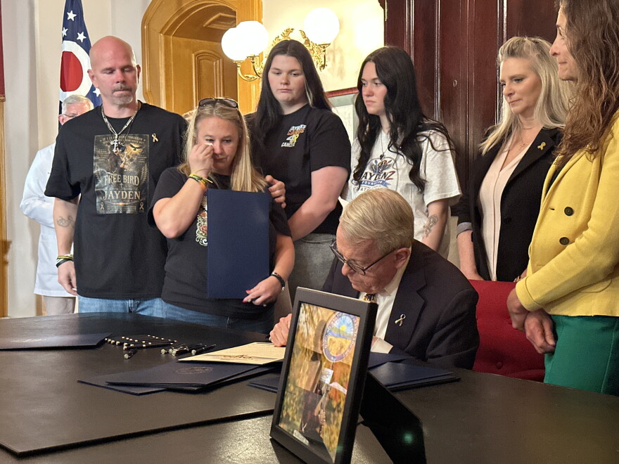 Gov. Mike DeWine signs an order recognizing National Childhood Cancer Awareness Month, with the Zurlinden family to his left.
