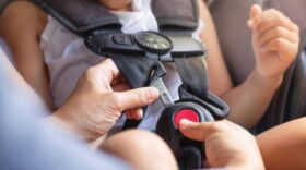 close up of car seat straps and buckles as parent secures child in seat 