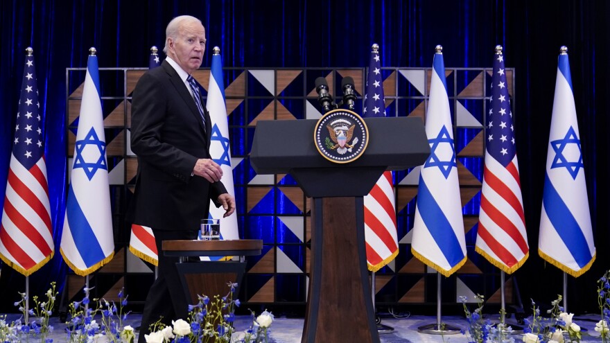 President Joe Biden walks to the podium to deliver remarks, with Israeli and American flags in the background.