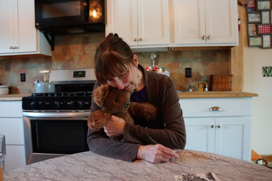 Woman hugging a teddy bear at a kitchen table