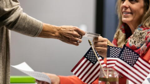 Person handing voter ID to election official. 