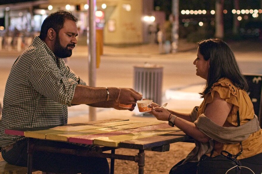 Man sits on the left, sharing food with woman sitting on the right as part of the Netflix show 'Indian Matchmaking'