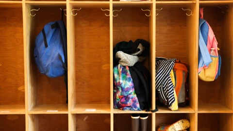 Backpacks and children's boots in wooden cubbyholes