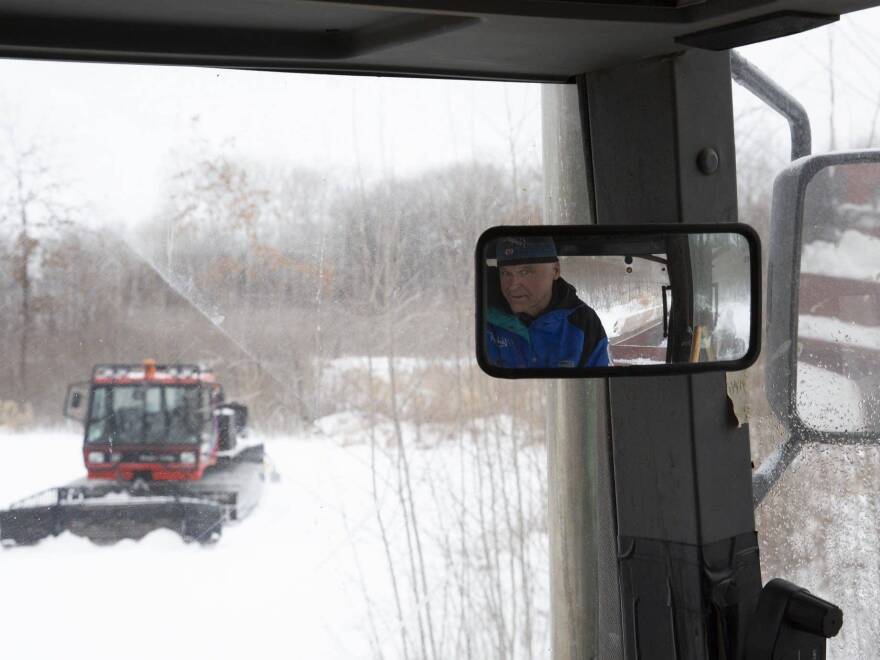 While sitting in a tractor, volunteer Don Olson waits for Lucas Olen to finish grooming a trail on Tuesday at the Vasaloppet Nordic Ski Center in Mora, Minn. Olson says a spreader holds about 15 cubic yards of snow, which will cover about 10 meters.