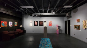 Paintings and sculptures from the Oops exhibit sit in a dimmed gallery