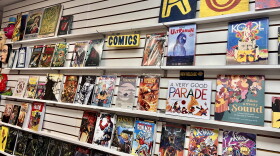 A wall display inside a comic shop features rows of comic books on shelves.