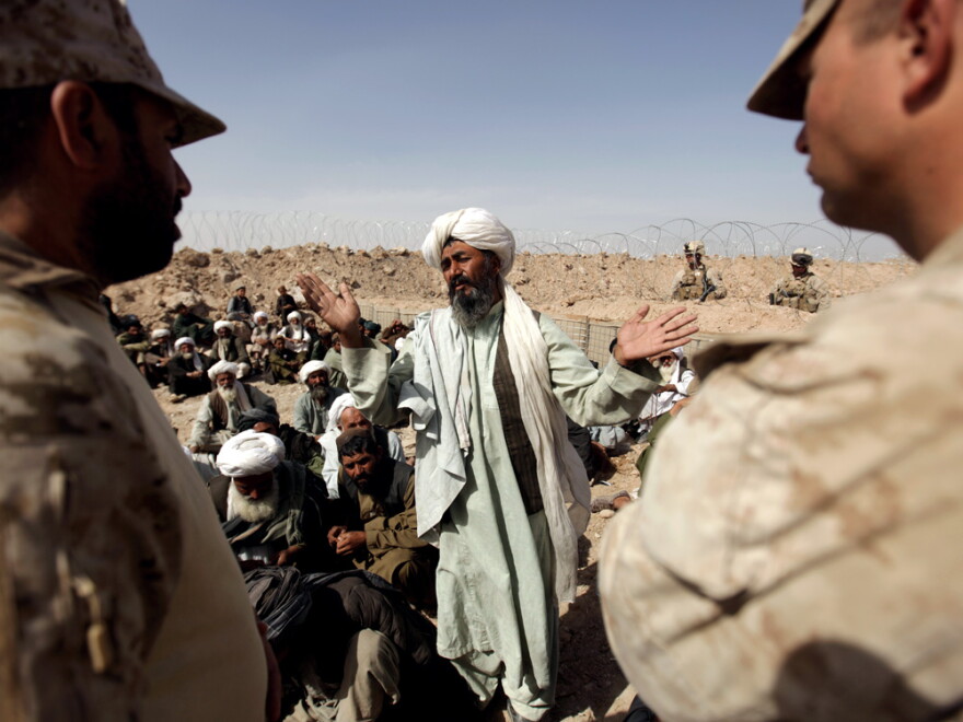 U.S. Marine commanding officer Capt. Stephen Karabin (right) and his translator listen to an elder from Trikh Nawar during a meeting with community leaders in the northeastern outskirts of Marjah on Saturday.