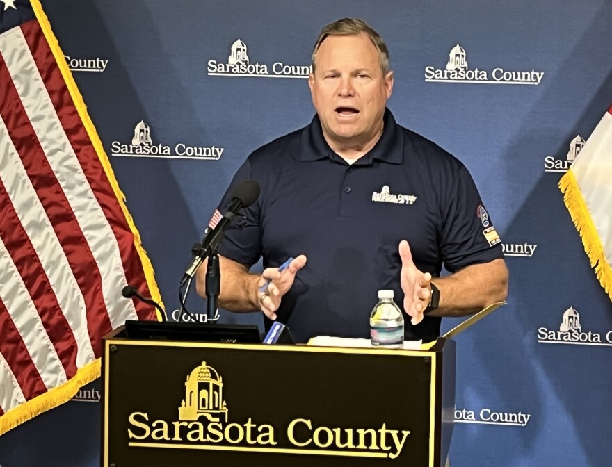 A man in a blue polo shirt speaks at a podium