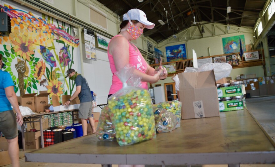 A person stands behind bags of marbles.