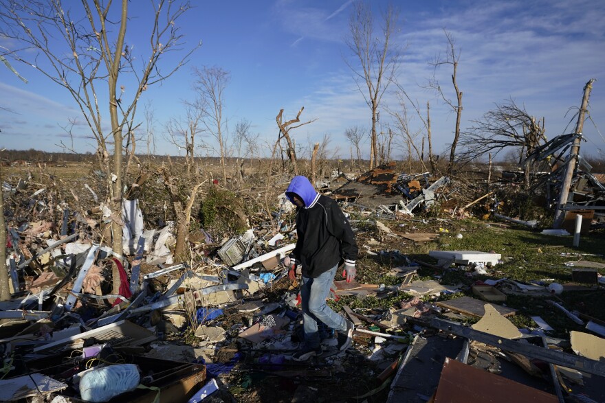 A person walks through the remains of several apartment units after a tornado damaged the area, in Mayfield, Ky.