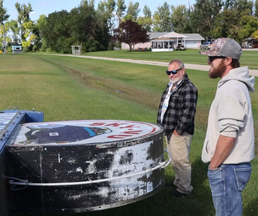 Steve Novak, left, and Chris Novak, right, look at the downed marquee of Sky-Vu in Warren, Minn., on Sunday. The wind's strength was so great that it bent over the metal poles that held up the sign. | MPR News
