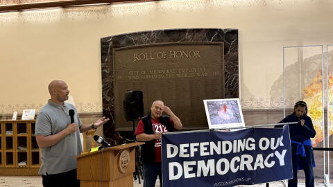 Harry Dunn is standing behind a podium, speaking to supporters about Jan.6