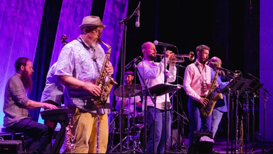 The PMAC Jazz Faculty playing onstage during a performance under blue/purple light.