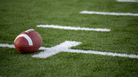 A brown leather american football on a green playing field