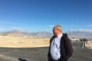 Man looks at construction site with mountains.