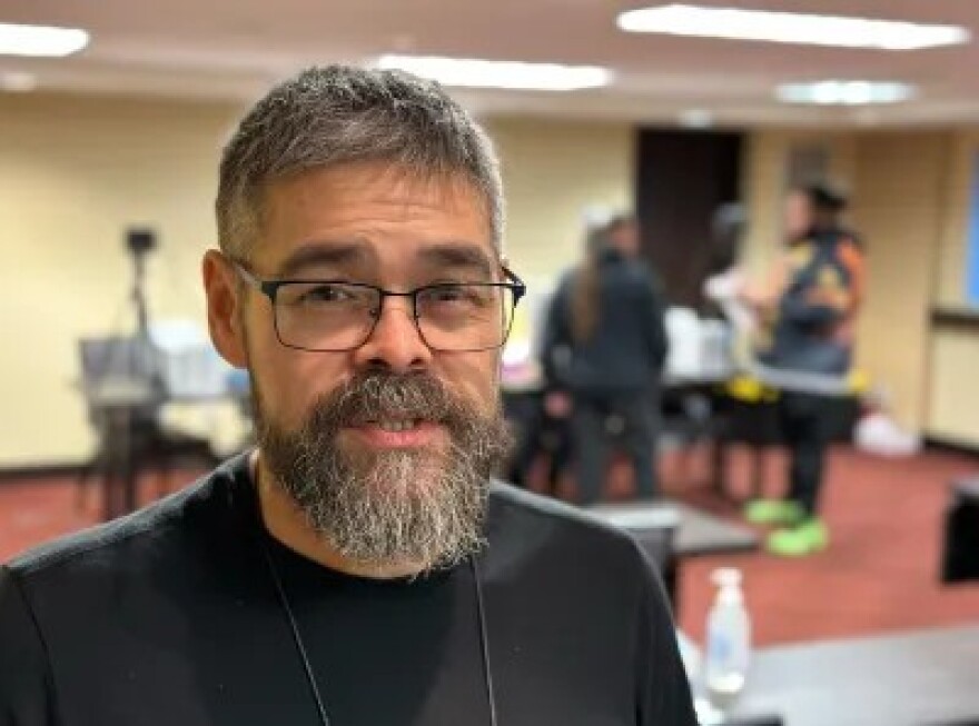 A bearded man with glasses looks at the camera.